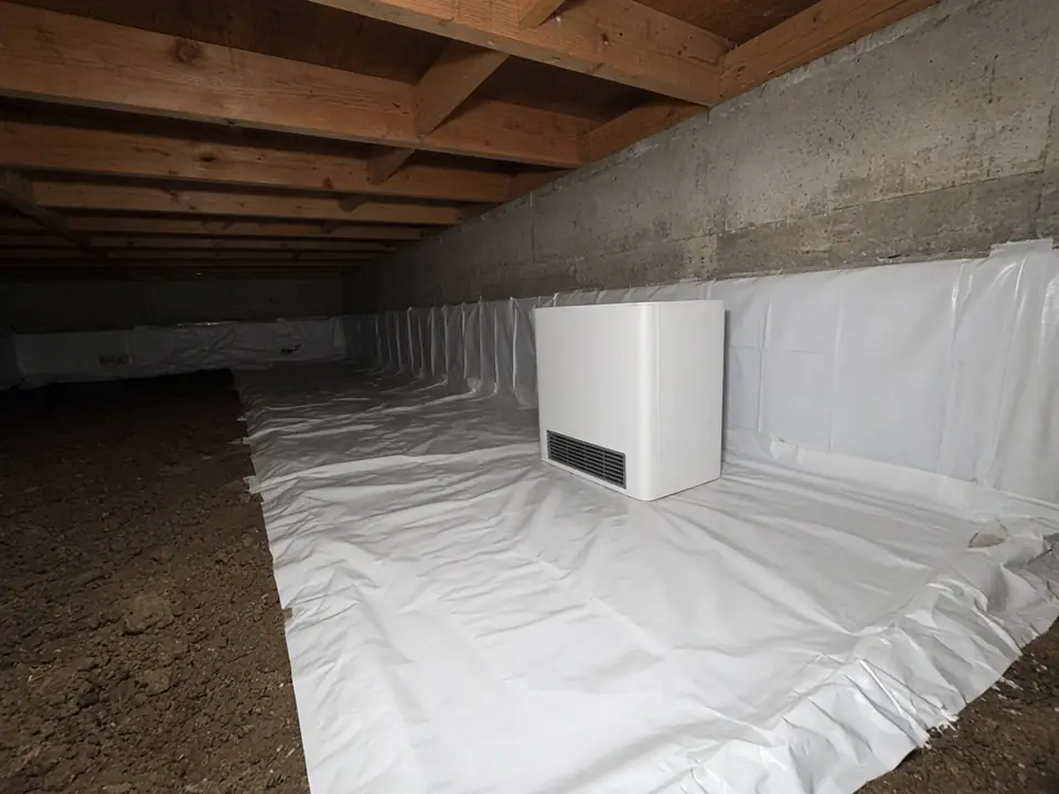Illustrative example of a crawl space with a white vapor barrier partly installed and a dehumidifier, showing what encapsulation can look like. Not work performed by this site.